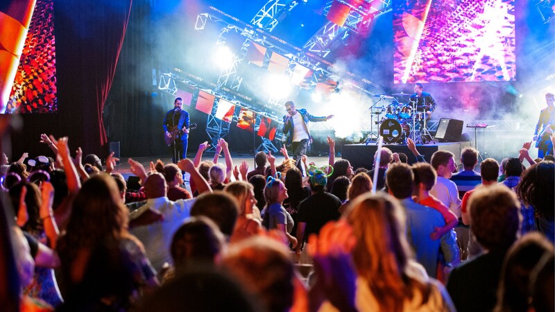 Uma multidão aplaudindo músicos que se apresentam em um palco