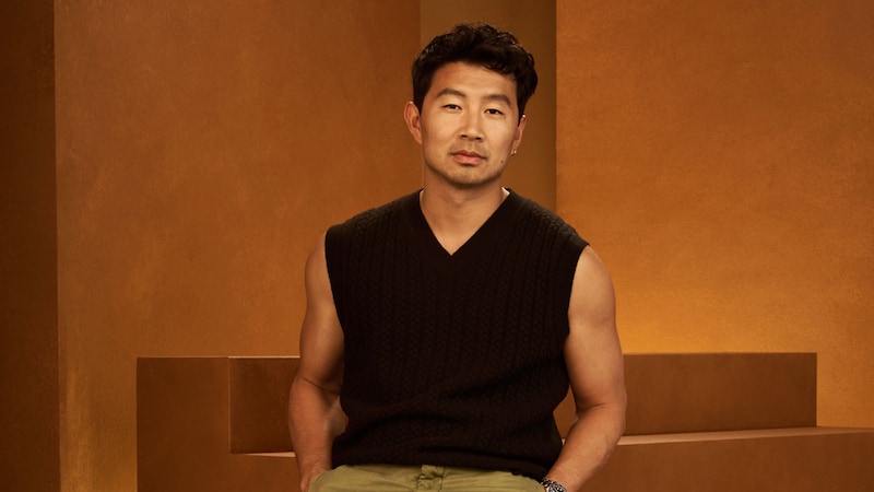 The Canadian actor Simu Liu leaning on a set of stairs