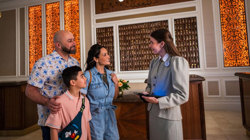 Family of 3 speaking to a Cast Member at a hotel’s front desk