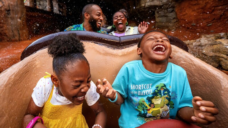  A family of 4 laughing as they ride Tiana’s Bayou Adventure