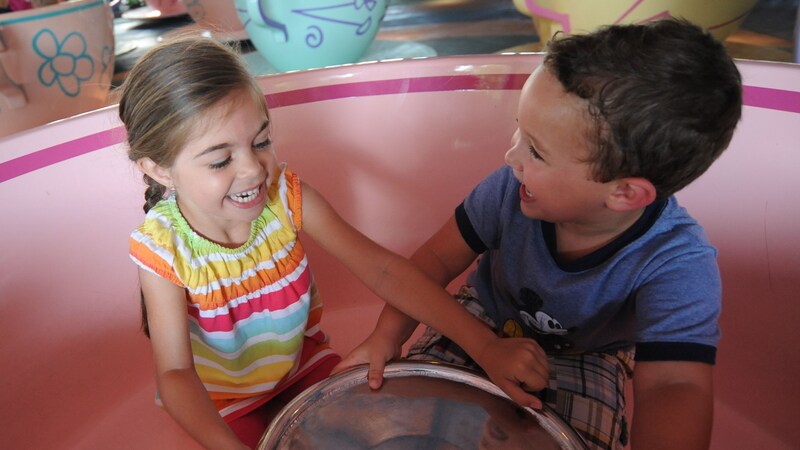  A young boy and girl laughing together while riding in a teacup at Mad Tea Party