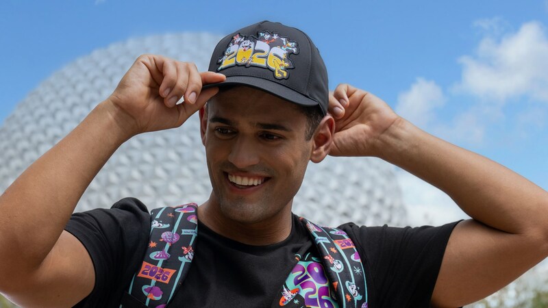 A man wearing a Mickey Mouse shirt, backpack and hat from the Mickey and Friends 2026 collection at Spaceship Earth in Epcot