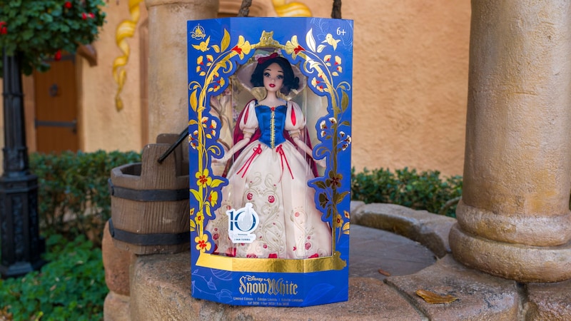 A Snow White doll in its packaging resting on the edge of a well