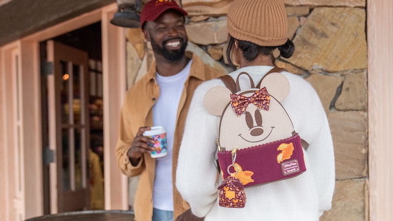 A Guest wearing a fall themed Minnie Mouse Loungefly mini backpack with leaf appliqués