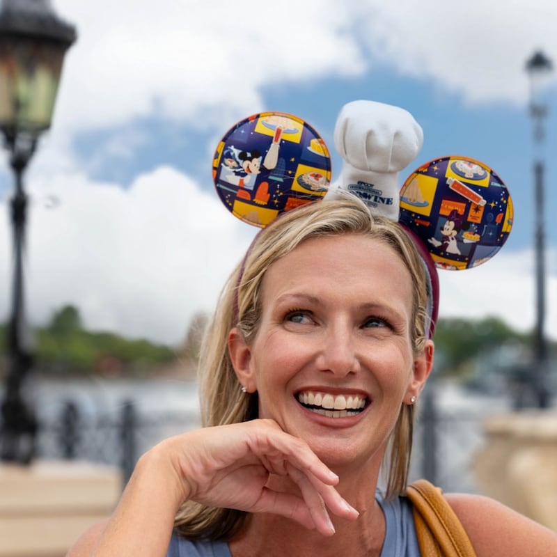 A Guest wearing an Epcot Food and Wine Festival Mickey Mouse ear headband near the World Showcase lagoon