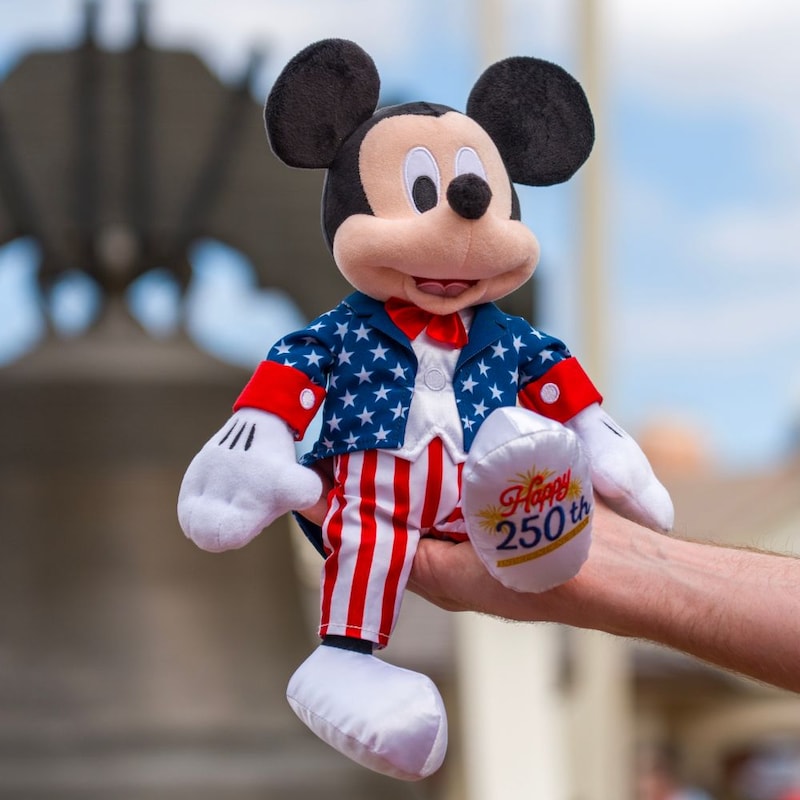 A hand holding a Mickey Mouse plushie commemorating America’s 250th Independence Day