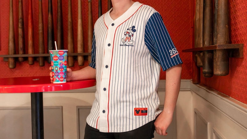 A Guest holding a drink and wearing a baseball jersey commemorating America’s 250th Independence Day