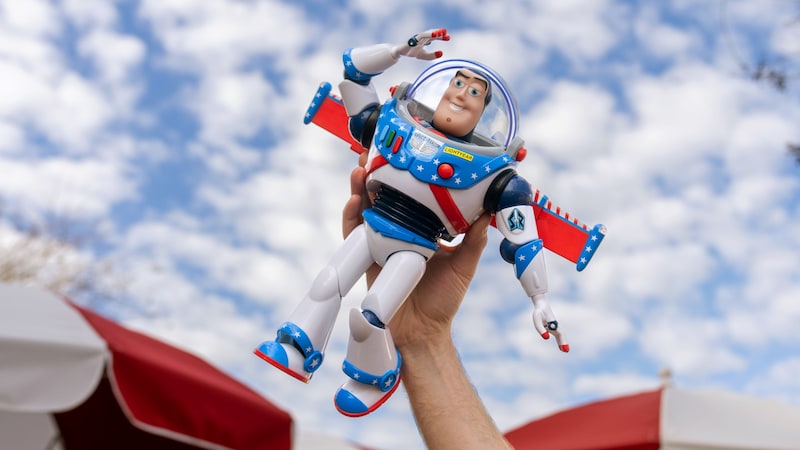 A hand holding a Buzz Lightyear toy in the air