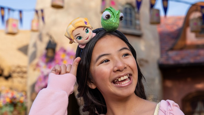 A Guest wearing a Minnie Mouse ear headband featuring Rapunzel and Pascal