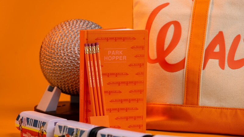 Walt Disney World merchandise, including a tote bag, pencils, a journal reading "Park Hopper” and a monorail figurine