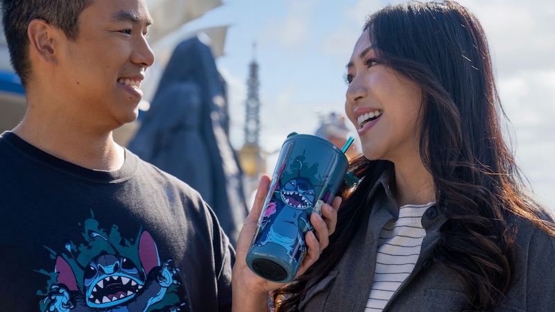 Two Guests facing each other, with one wearing a shirt featuring Stitch and holding a matching cup