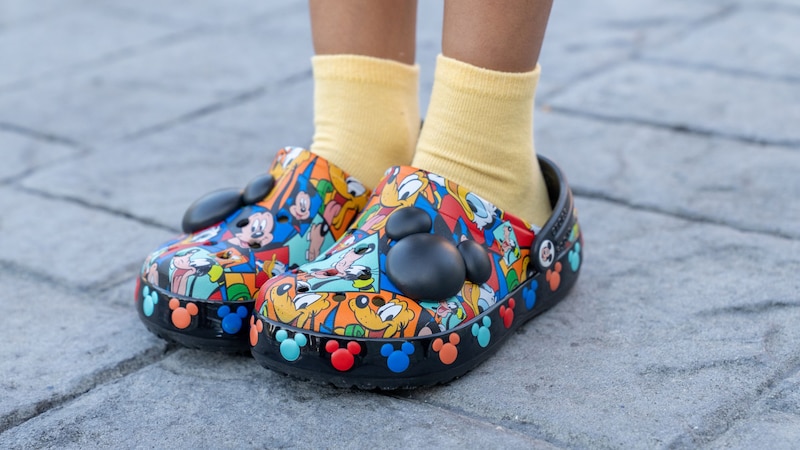 A child's feet wearing Disney Crocs with Mickey Mouse charms