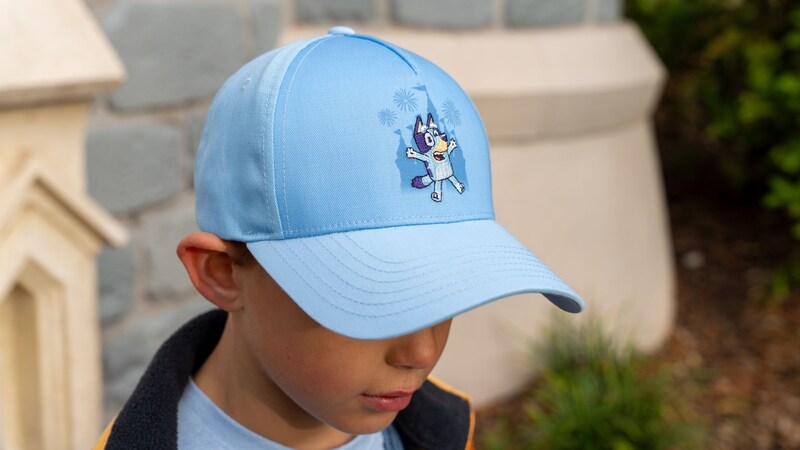 A young child wearing a baseball cap featuring Bluey