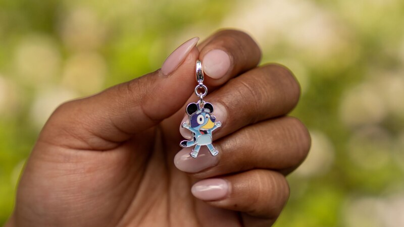 A hand holding a small charm featuring Bluey