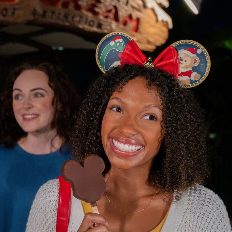Two women smiling with chocolate Mickey Mouse ice cream bars near Dinosaur Gertie's Ice Cream of Extinction