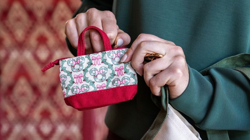 A hand holding a small bag printed with Minnie Mouse wreaths and bows