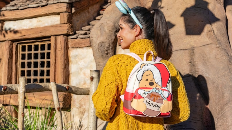 A Guest wearing a festive Winnie the Pooh backpack with a honey pot design