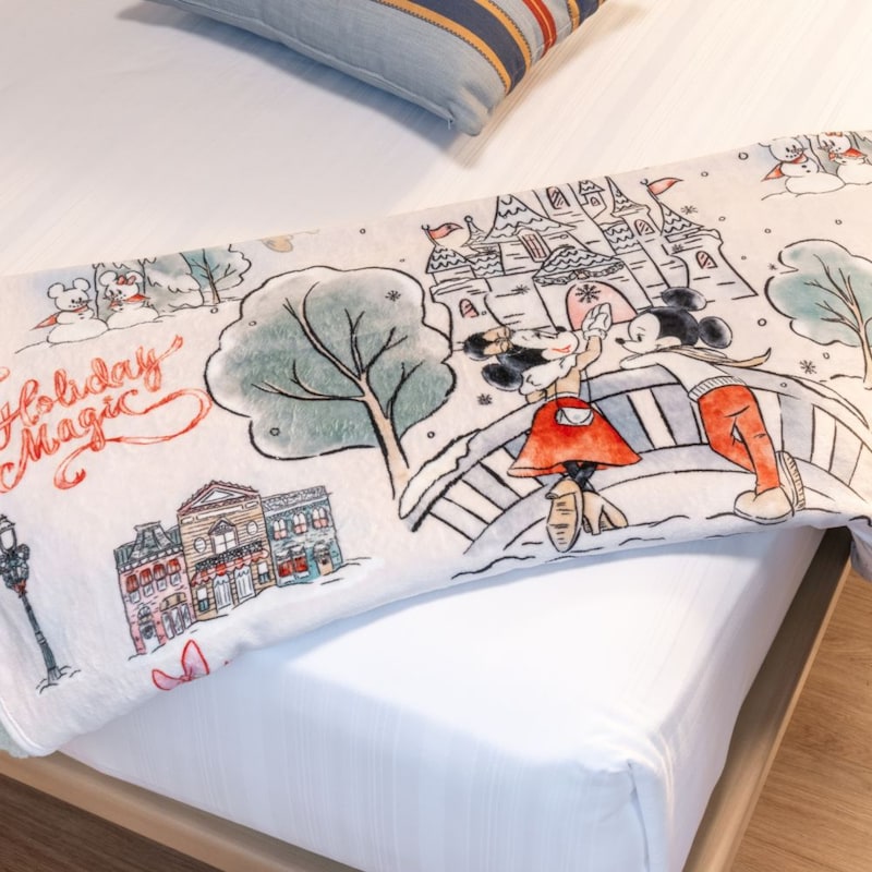 A holiday blanket illustrated with Mickey Mouse and Minnie Mouse dancing on a bridge