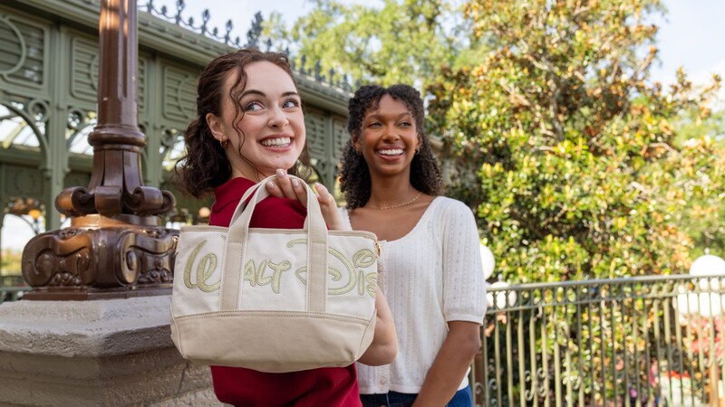 A woman holding a tote bag embroidered with Walt Disney World logo