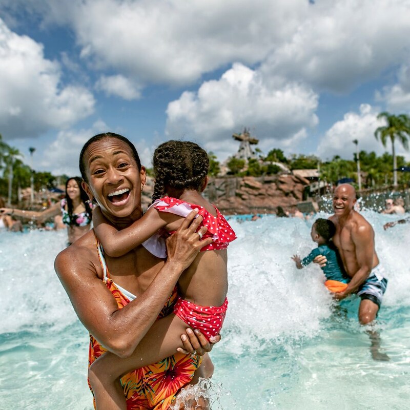 Un Visitante lleva a un niño mientras salen de la piscina Typhoon Lagoon Surf en Disney’s Typhoon Lagoon Water Park