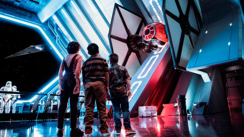 Three kids gaze at a Tie Fighter ship at the attraction Star Wars Rise of the Resistance.