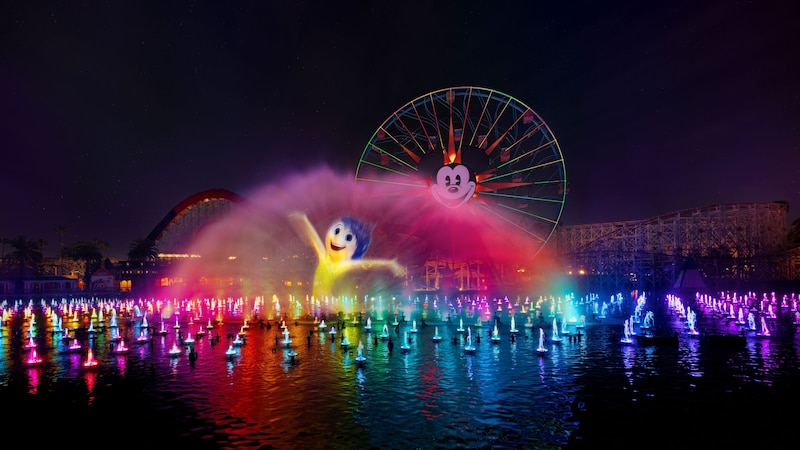 A World of Color One show featuring illuminated water fountains and a projection of Joy from ′Inside Out′ on a mist screen near Pixar Pal A Round Swinging at Disney California Adventure Park