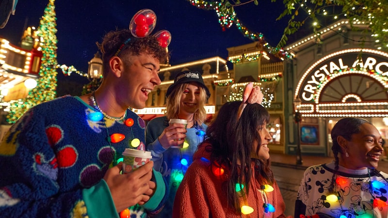 Guests wearing Christmas themed attire while riding on a parade float down Main Street, USA