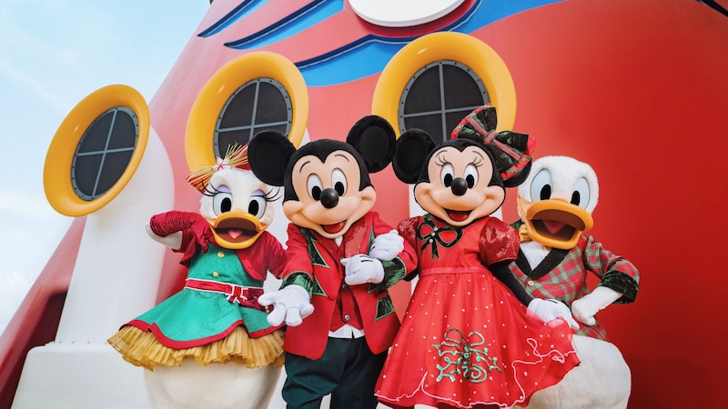 Mickey Mouse, Minnie Mouse, Donald Duck and Daisy Duck dressed in their holiday attire while posing together on a Disney cruise ship