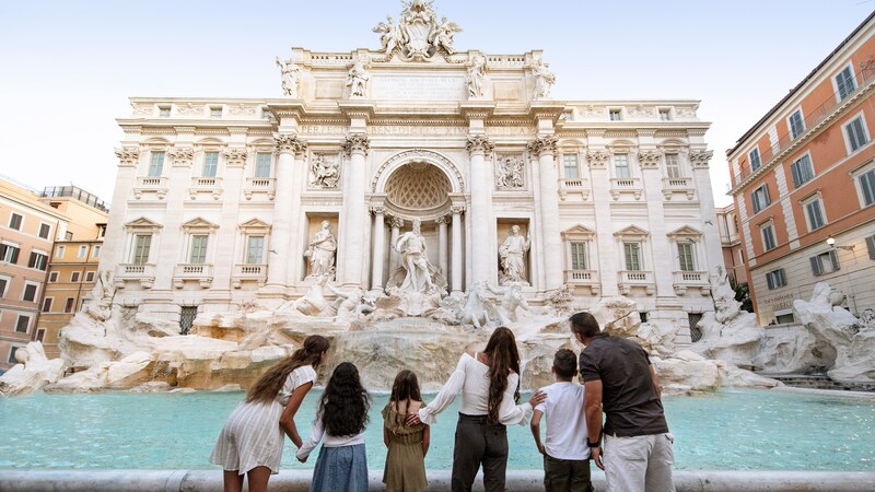 A family of 6 stands in front of Trevi Fountain in Rome, Italy