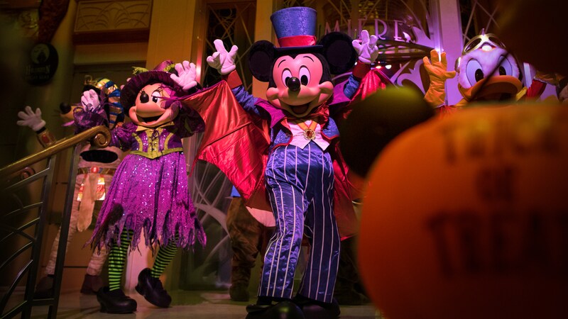 Mickey Mouse in top hat and tails standing next to Minnie Mouse dressed as a not so scary witch