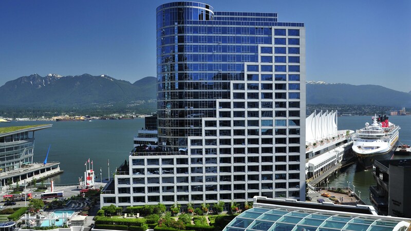 A Disney cruise ship docked next to the glass and steel Fairmont Waterfront Vancouver