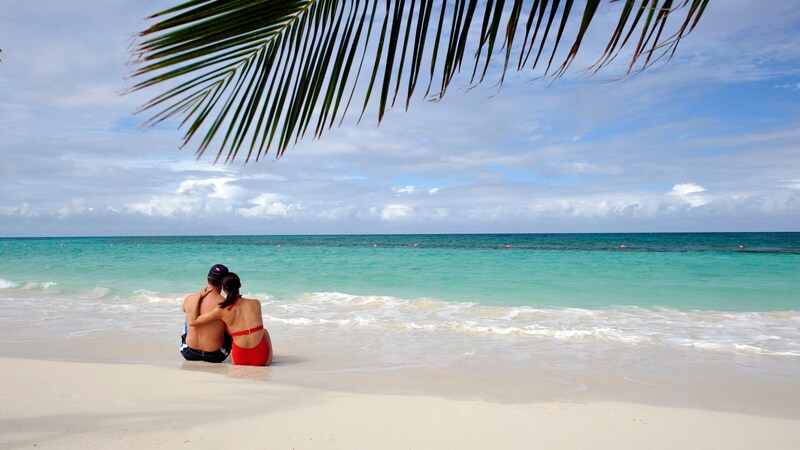 A couple sits along the shoreline of an adult only beach on Disney Castaway Cay in The Bahamas