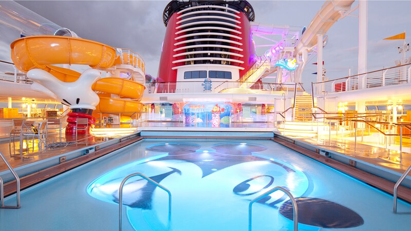 A winding waterslide next to a swimming pool with an image of Mickey Mouse on its bottom