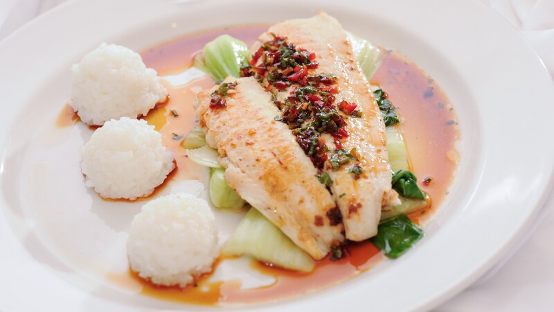 Grilled fish atop bok choy in a delicate sauce with 3 small scoops of rice