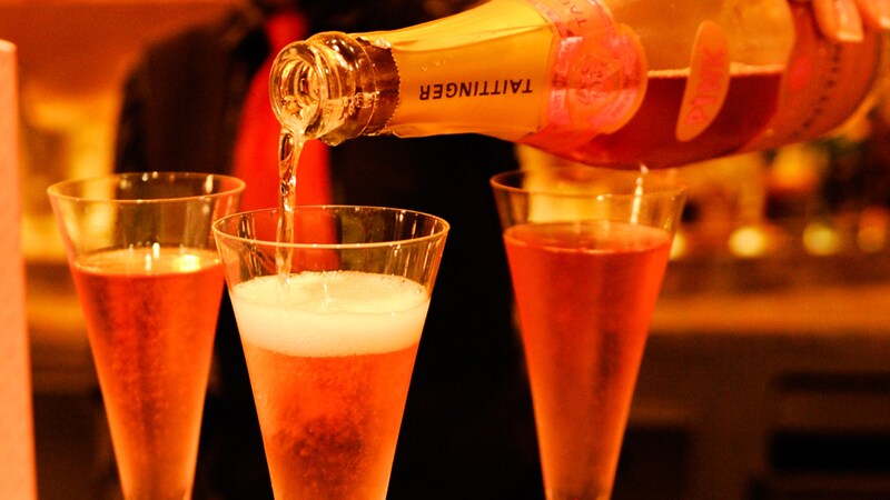 A bottle of Taittinger Champagne being poured into glass flutes