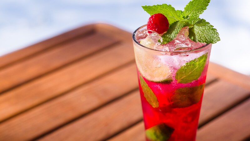 A mixed raspberry, lime and mint cocktail served on the rocks in a tall glass