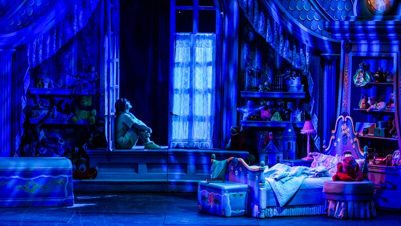 A young girl sits in her open bedroom window at night, imagining the magic of dreams.