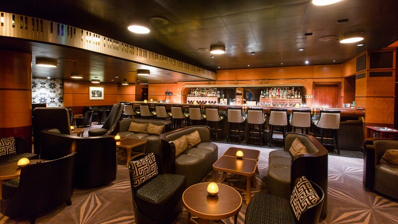 A large, spacious lounge features leather sofas, comfortable chairs and a long bar