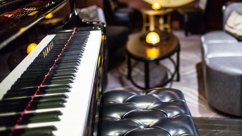 The keyboard of a grand piano and a bench