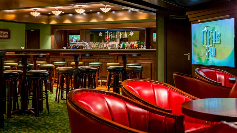 An Irish Pub called O Gills has lots of bar tables with stools and chairs with cocktail tables