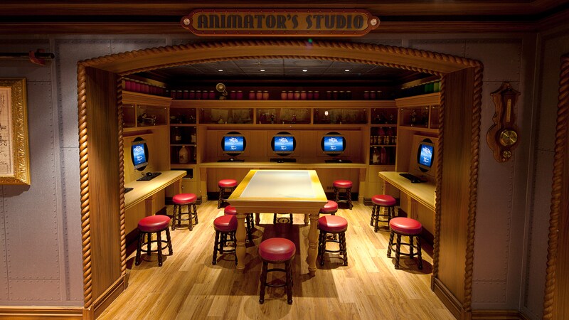 A Disney themed arts and crafts area with computer stations, stools, a large table and shelves stocked with art materials