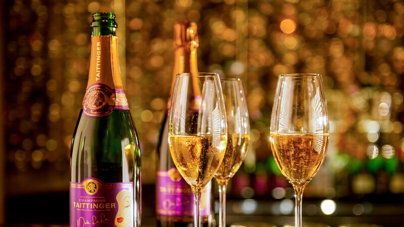 Two bottles of Tattinger champagne sit next to 4 full champagne flutes