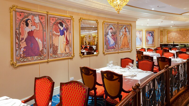 Portraits of Disney princesses on a wall by dining tables and chairs embellished with gilded emblems