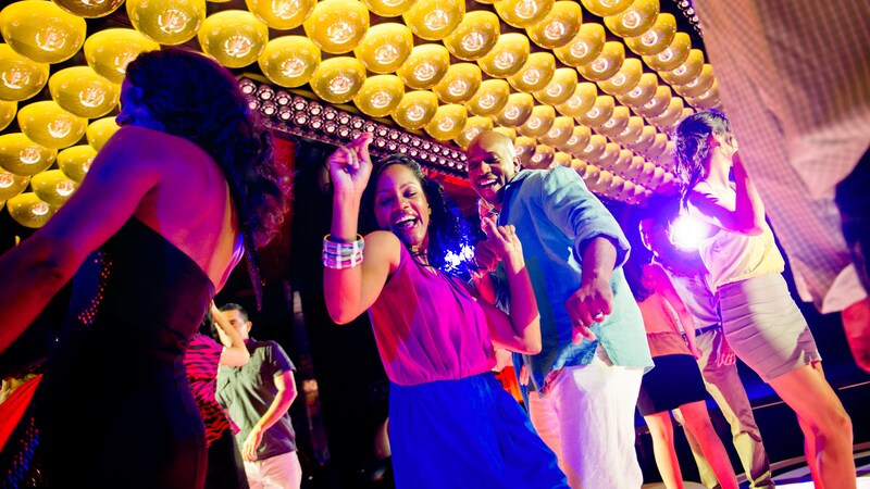 A couple dances under bright lights in an onboard nightclub