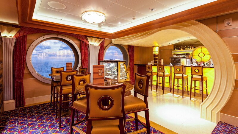 A lounge with tall bar tables and high back stools has large porthole windows