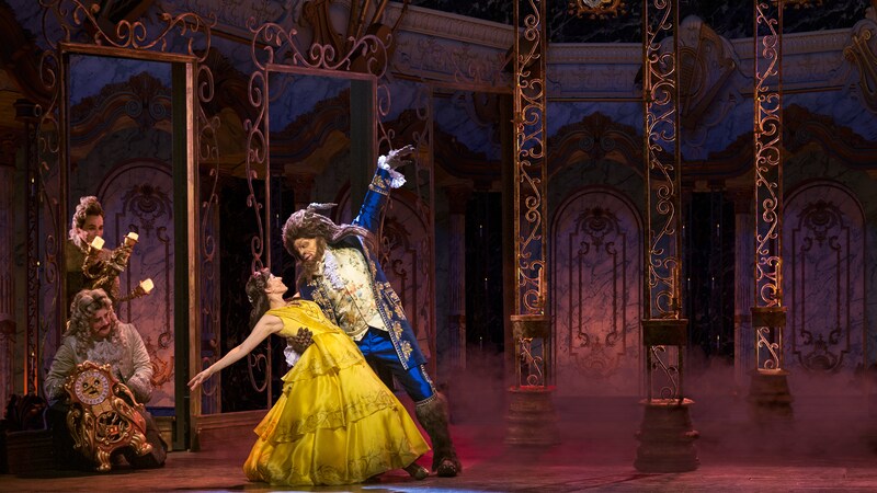 Performers dressed as Belle and Beast dance near performers dressed as Lumière and Cogsworth