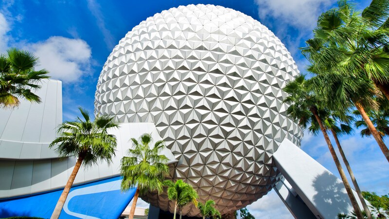 Spaceship Earth with palm trees in front of it against a blue sky at Epcot theme park