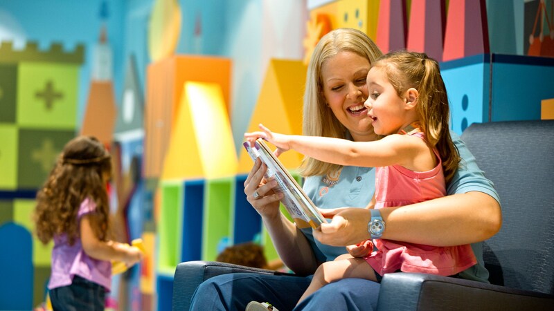 A woman reading to a young girl in a children's play room