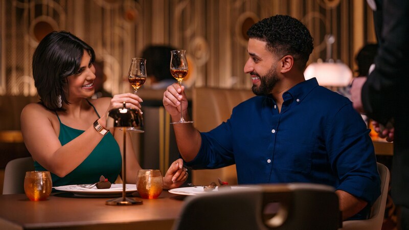 A couple raising glasses to each other before eating dessert at Palo Steakhouse