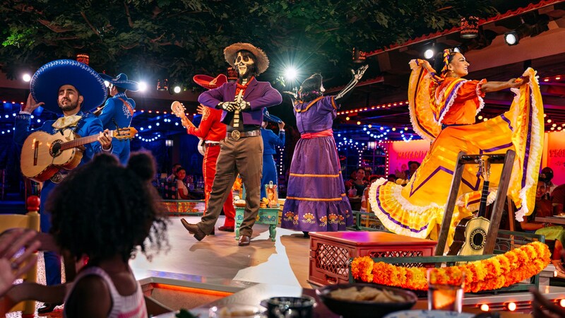 Musicians and dancers performing onstage while Guests dine at Plaza de Coco on the Disney Treasure